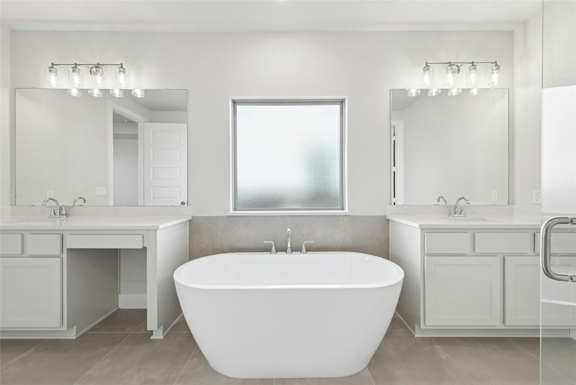 1528 Rodeo Ridge Drive Georgetown, TX 78628 - Photo 9 of 28 Bathroom featuring two vanities, light tile patterned floors, a soaking tub, and wainscoting