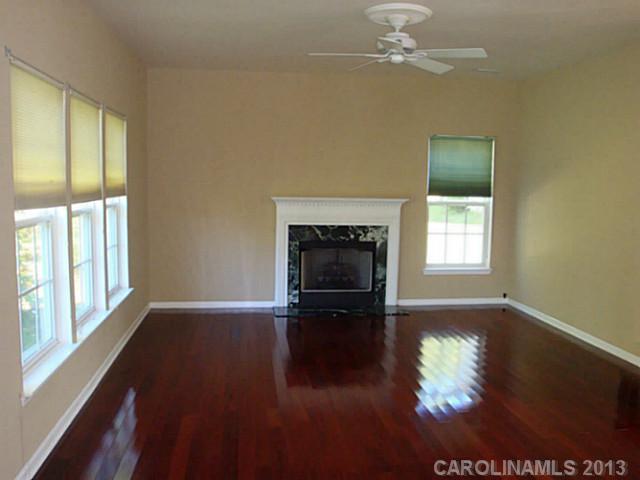 3741 Marbury Road Charlotte, NC 28269 - Photo 2 of 16 an empty room with wooden floor fireplace and windows