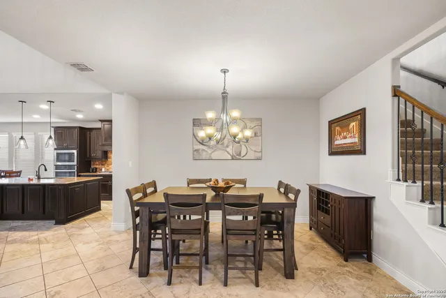 a dining room with wooden floor a chandelier a wooden table and chairs