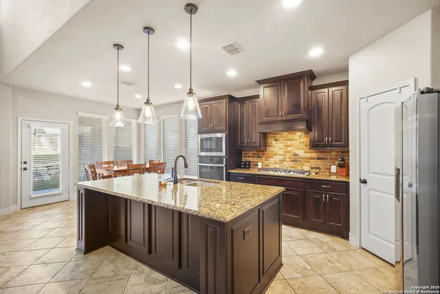 a kitchen with kitchen island granite countertop a sink refrigerator and cabinets
