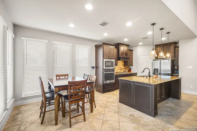 a dining hall with stainless steel appliances granite countertop a table and chairs