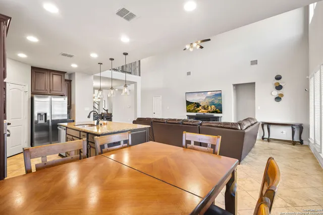 a living room with stainless steel appliances furniture a rug and a kitchen view