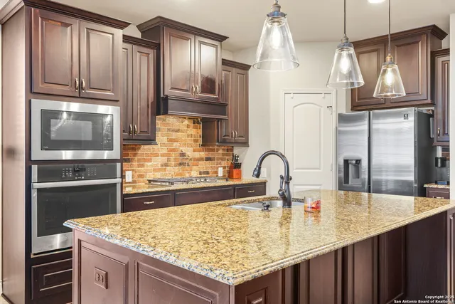 a kitchen with kitchen island granite countertop a wooden cabinets and refrigerator