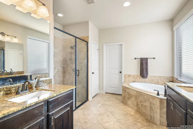 a bathroom with a sink double vanity granite tub shower and mirror