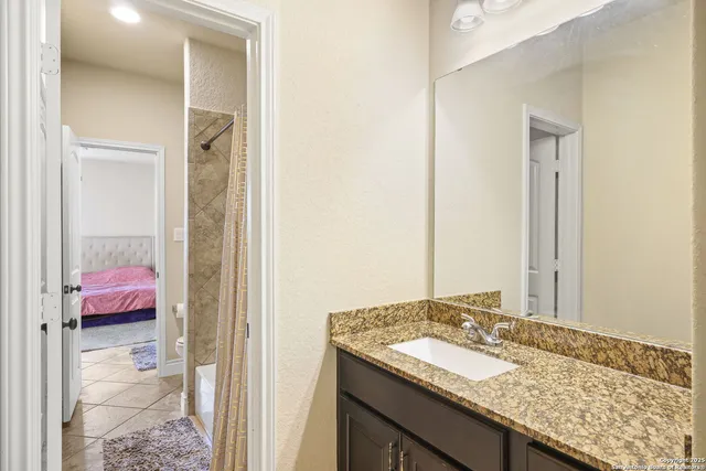 a en suite bathroom with a granite countertop sink and a mirror