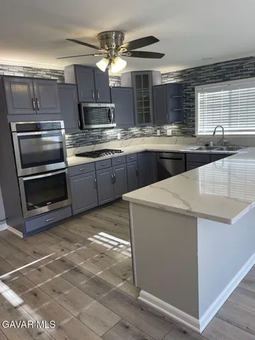 a kitchen with kitchen island granite countertop a sink cabinets and stainless steel appliances