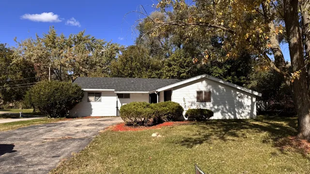 a view of a house with a yard and large trees