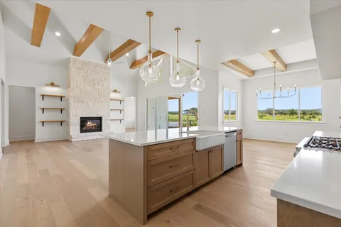 a view of a kitchen with kitchen island a sink wooden floor and a large window