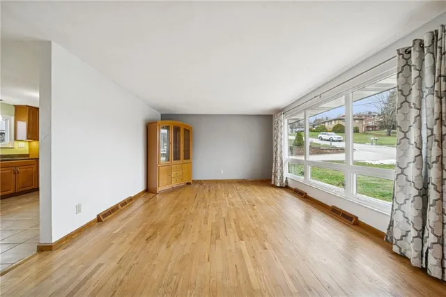 a view of an empty room with glass door and wooden floor