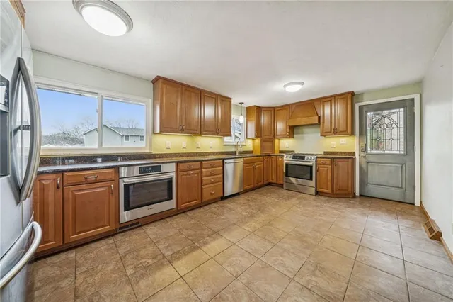 a kitchen with stainless steel appliances granite countertop a stove sink and cabinets