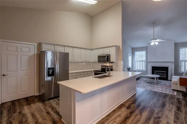 a large kitchen with a refrigerator a stove a sink dishwasher a dining table and chairs with wooden floor