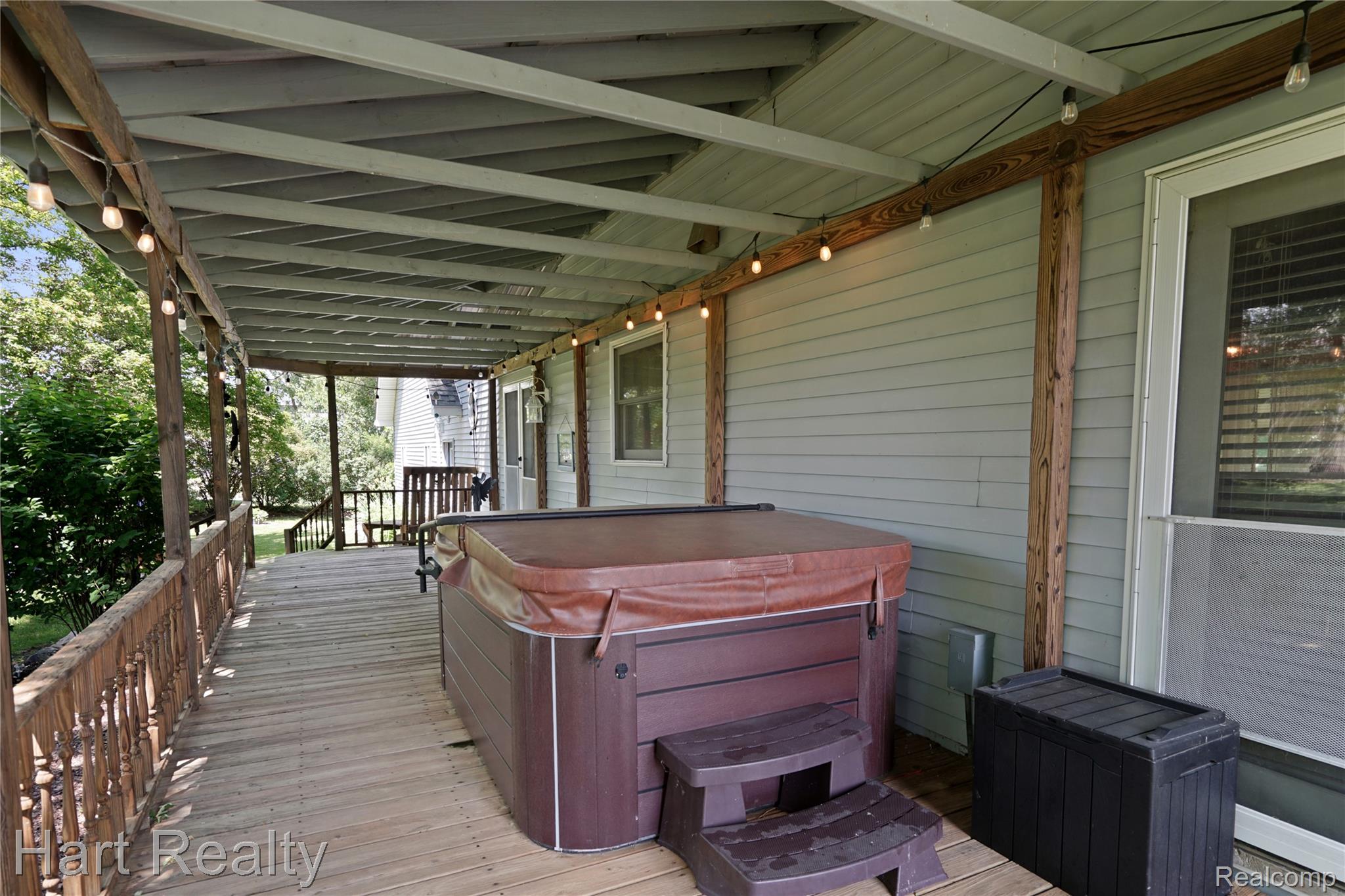 7167 Brown School Road North Branch, MI 48461 - Photo 40 of 51 Expansive covered deck featuring a hot tub, wood railing, and string lighting