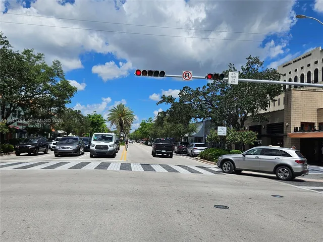 a palm tree sitting in front of a house with a trees