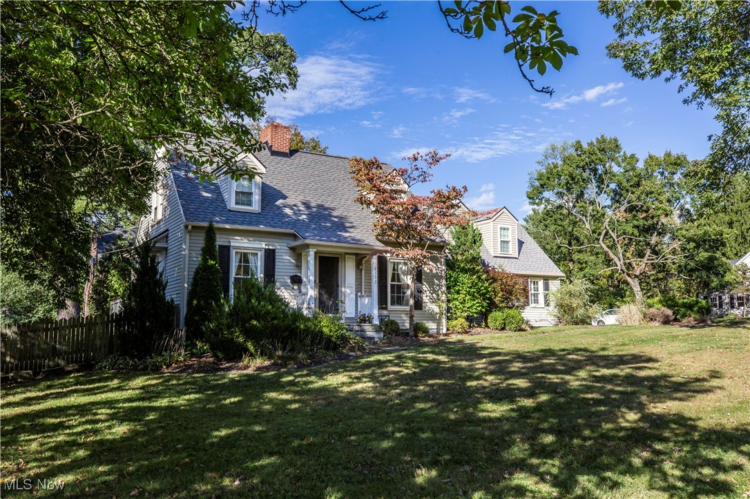 New england style home featuring a chimney and roof with shingles