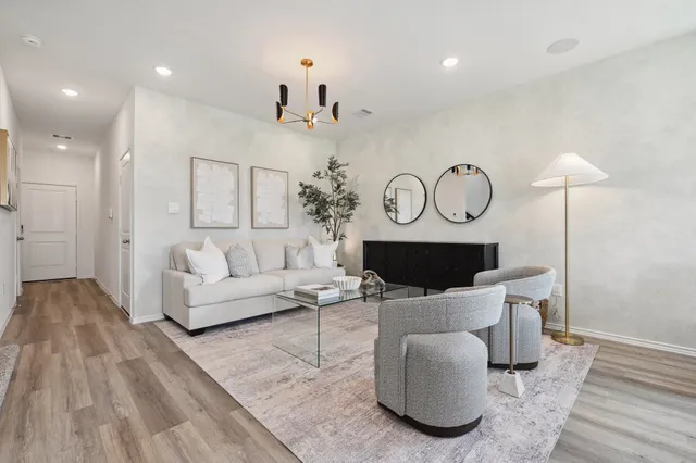 a living room with furniture a flat screen tv and a wooden floor