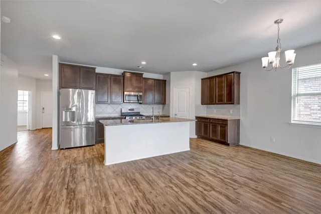 a large kitchen with stainless steel appliances granite countertop a stove and a wooden floors
