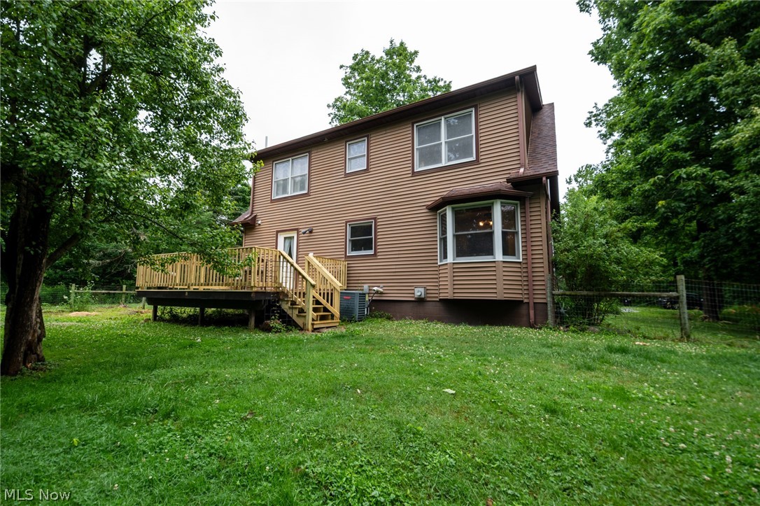 14027 Mayfield Road Huntsburg, OH 44046 - Photo 40 of 50 Rear exterior featuring brown siding, a multi-level wood deck with railings and stairs, a bay window, and surrounding mature trees