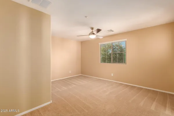 an empty room with windows and ceiling fan