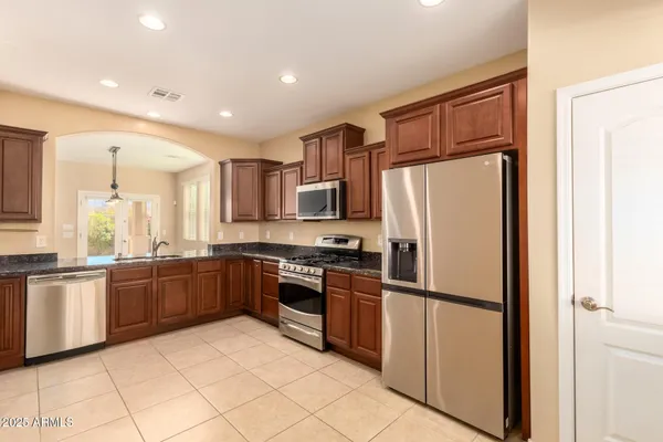 a large kitchen with stainless steel appliances granite countertop a refrigerator and a stove top oven