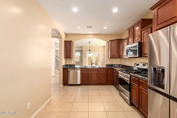 a large kitchen with stainless steel appliances granite countertop a stove a sink and a refrigerator