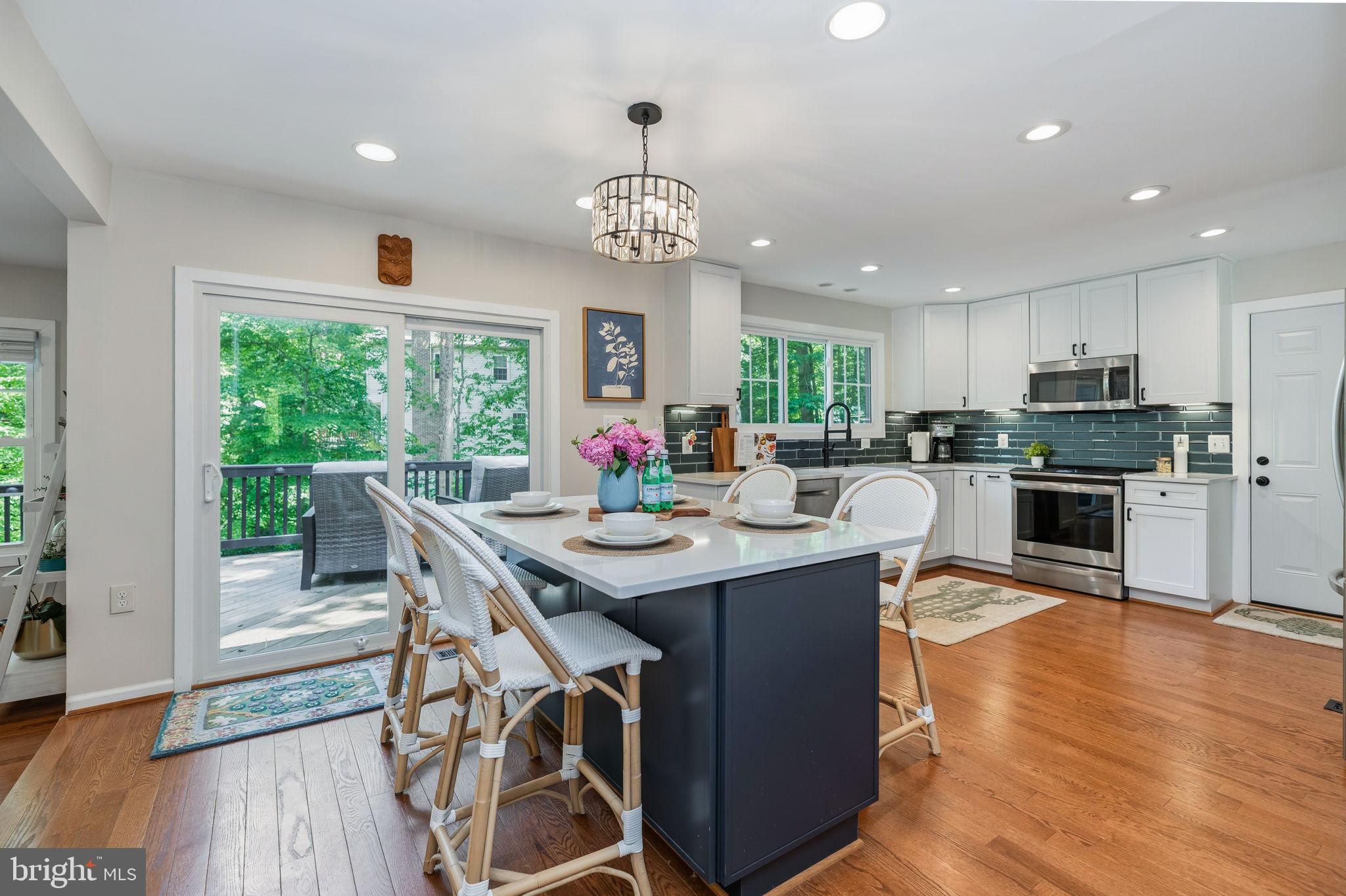 7603 Modisto Lane Springfield, VA 22153 - Photo 10 of 57 a kitchen with stainless steel appliances granite countertop a kitchen island hardwood floor sink stove dining table and chairs