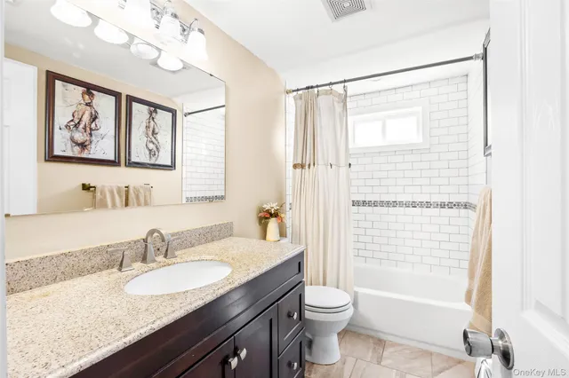a bathroom with a granite countertop sink a toilet a mirror a vanity a bath tub and shower