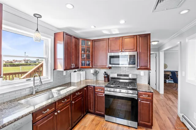 a kitchen with stainless steel appliances granite countertop a stove a sink and a microwave