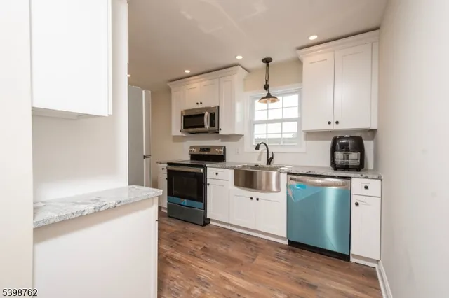 a kitchen with granite countertop a refrigerator stove top oven and sink