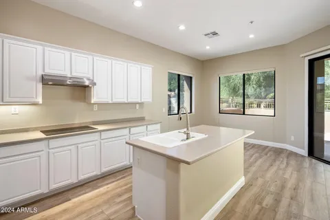 a kitchen with stainless steel appliances granite countertop a sink dishwasher and white cabinets with wooden floor