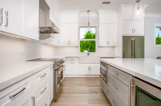 a kitchen with a sink dishwasher and white cabinets with wooden floor