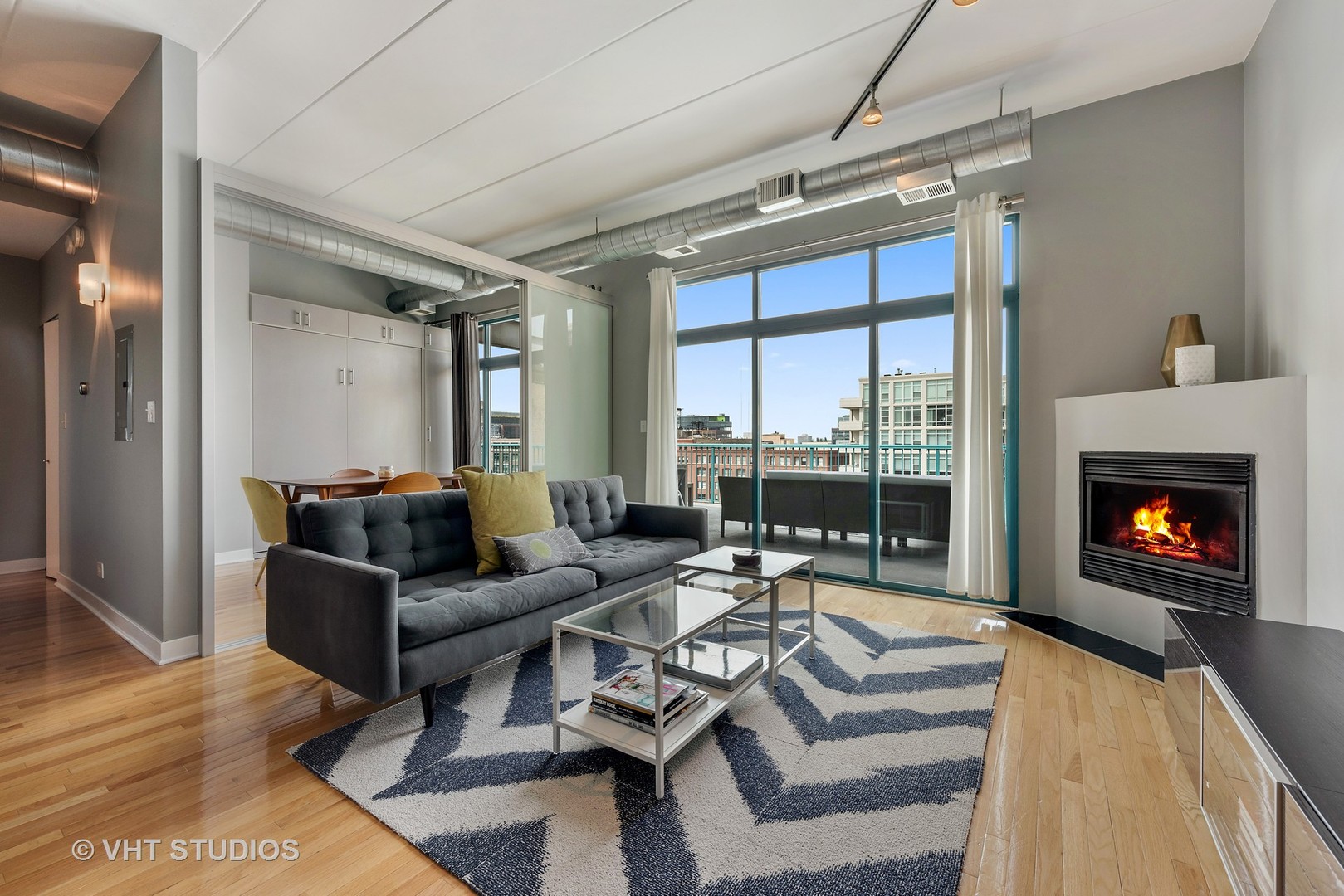 920 West Madison Street, Unit F8 Chicago, IL 60607 - Photo 2 of 14 a living room with furniture a fireplace and a floor to ceiling window