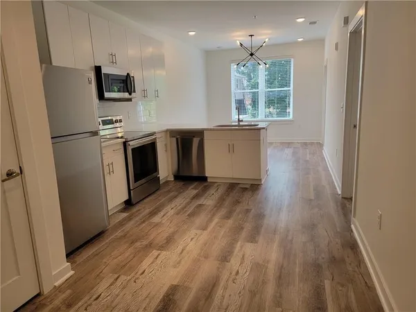 a kitchen with kitchen island wooden floors appliances and window