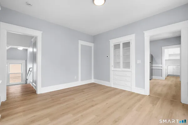 a view of an empty room with wooden floor and a window