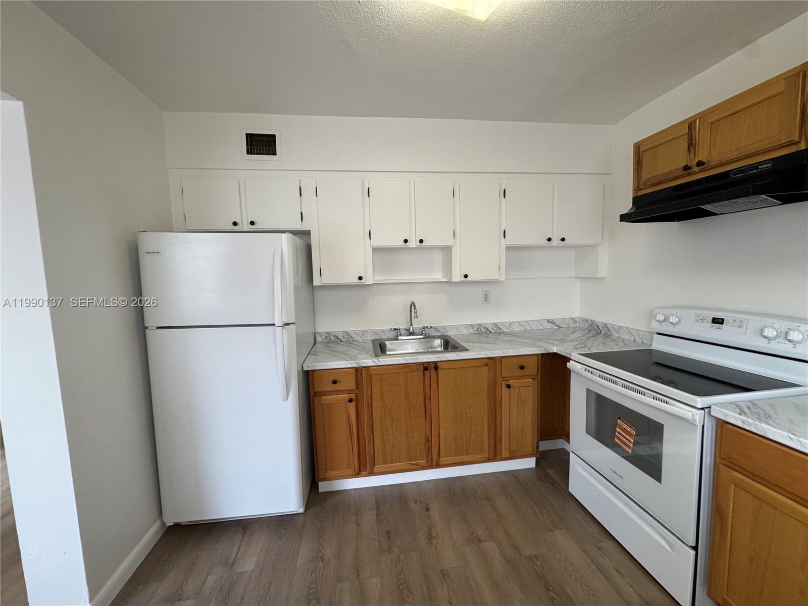 4080 Southwest 2nd Terrace, Unit 6 Miami, FL 33134 - Photo 3 of 14 a kitchen with stainless steel appliances granite countertop a refrigerator a stove a sink and white cabinets