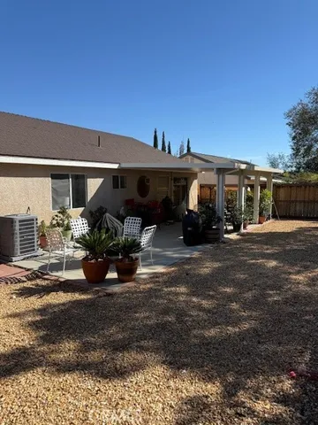 a view of a patio with table and chairs potted plants and floor to ceiling window and wooden fence