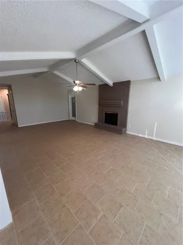 a view of an empty room with a fireplace and a fan