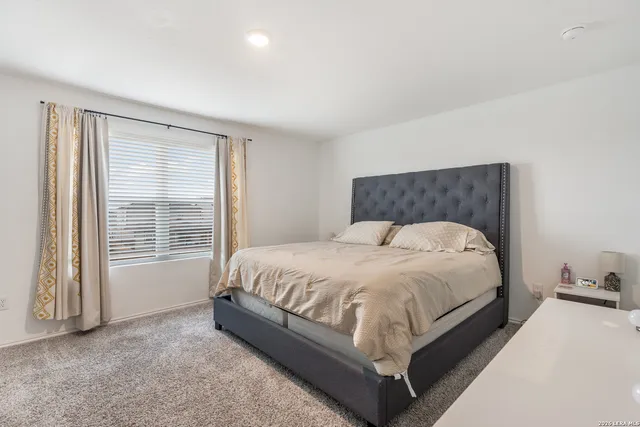 a bed sitting in a spacious bedroom next to a window