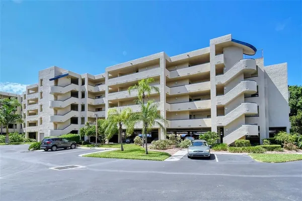 a front view of multi story residential apartment building with yard and traffic signal