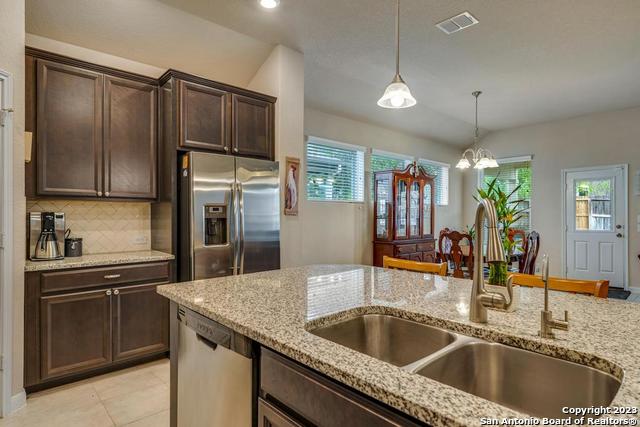 12515 Ponder Ranch San Antonio, TX 78245 - Photo 12 of 27 a kitchen with granite countertop a sink and refrigerator
