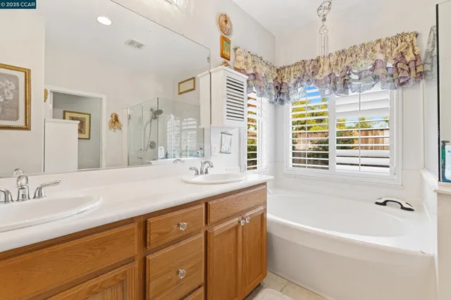 a bathroom with a granite countertop sink mirror bathtub and next to a window