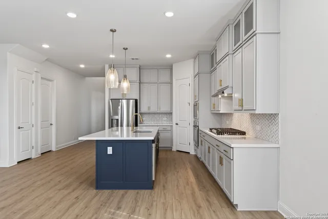 a kitchen with kitchen island a counter top space a sink stainless steel appliances and cabinets