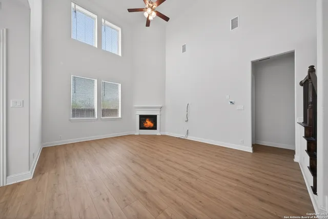 an empty room with wooden floor fan and windows