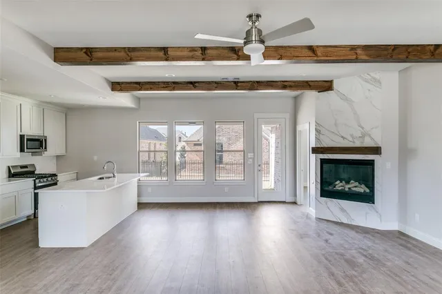 a living room with stainless steel appliances granite countertop a stove top oven a sink and a fireplace