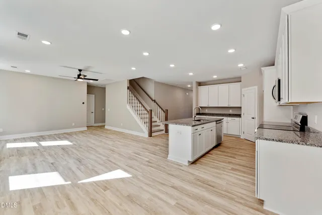 a large kitchen with stainless steel appliances kitchen island a large counter top and wooden floors