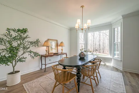 a kitchen with stainless steel appliances granite countertop a kitchen island a stove a refrigerator a sink a dining table and chairs with wooden floor