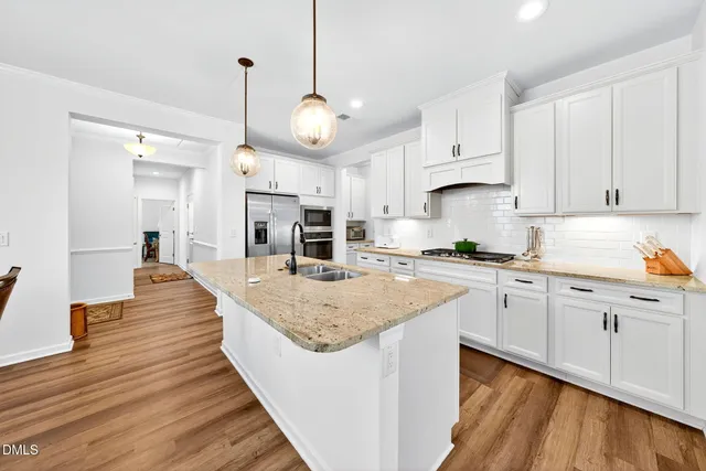 a large kitchen with kitchen island a stove a sink dishwasher and a fireplace with wooden floor