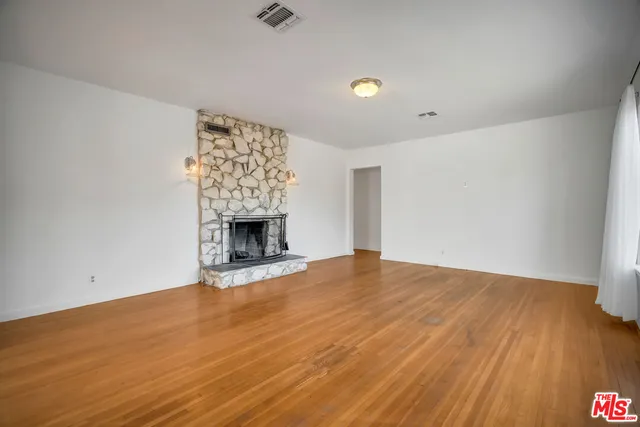 a view of an empty room with wooden floor and a fireplace