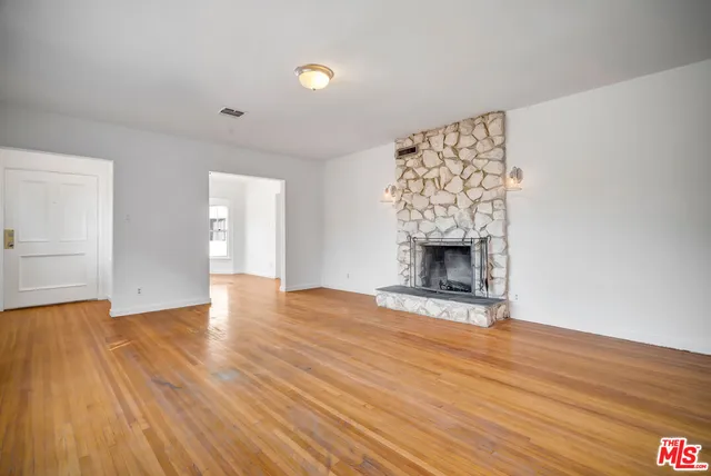 a view of a livingroom with wooden floor and a fireplace