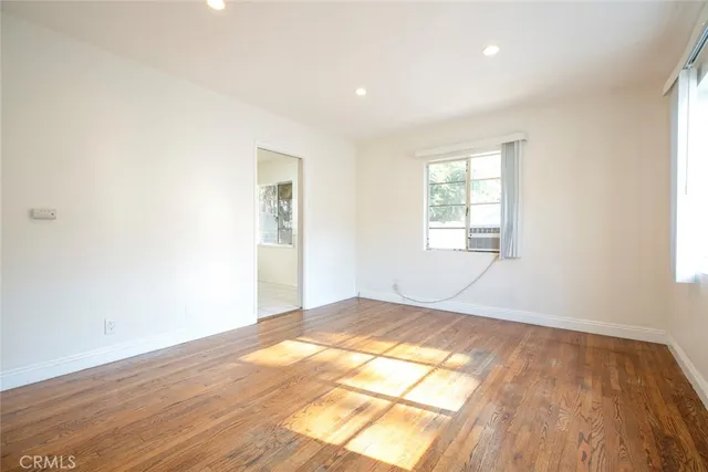 an empty room with wooden floor windows and entrance