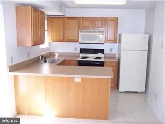 a kitchen with a refrigerator a stove a sink a counter top space and a window